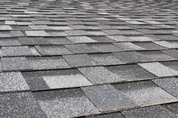 Close-up view of gray asphalt roof shingles arranged in an overlapping pattern, ideal for Commercial Roofing Services.